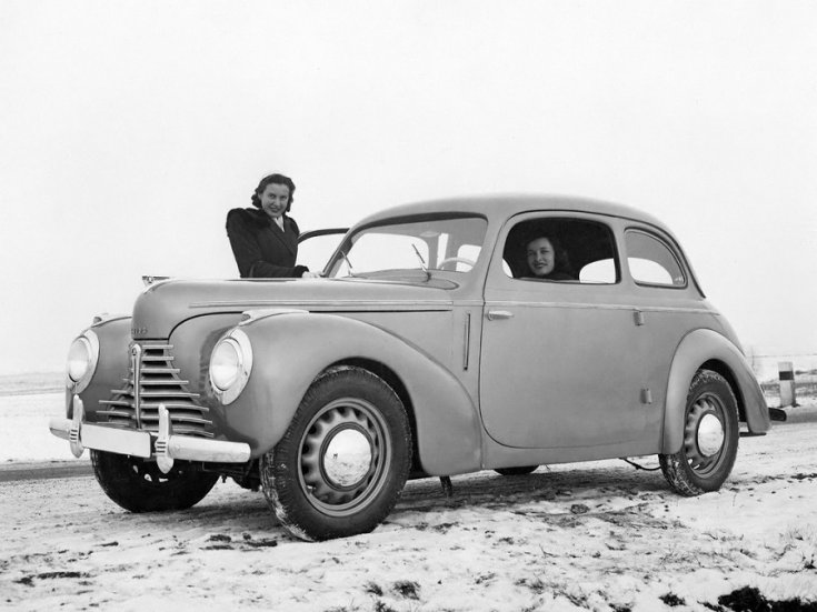1946 Skoda 1101 Tudor, fekte fehér kép, elölnézet, oldalnézet, balról, alulról fotózva, háttérben pusztaság, mellette 2 nő