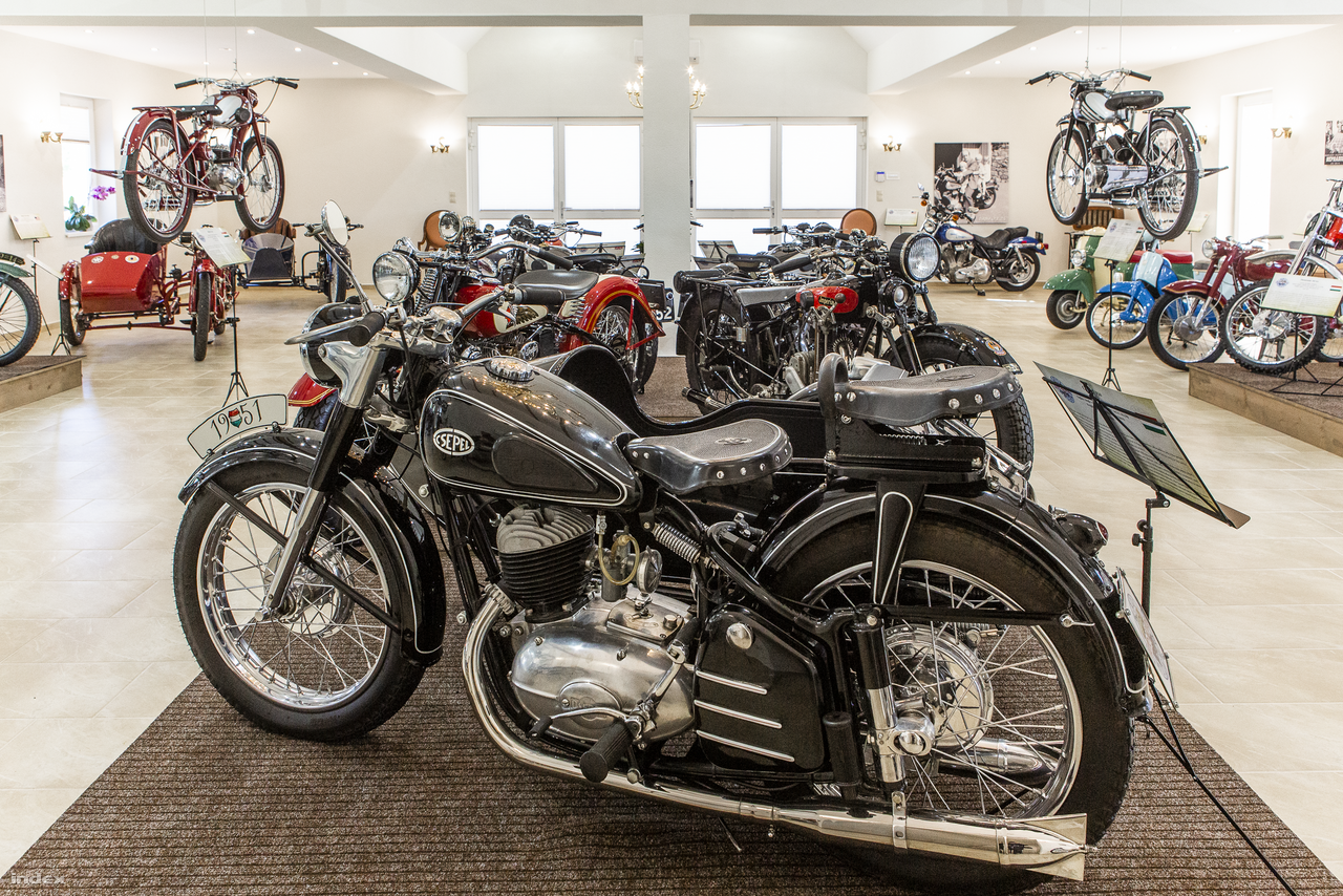 Ez az 1951-es oldalkocsis Csepel 250 talán a magyar motorkerékpárok egyik legszebbike. 1951-től 1953-ig gyártották, és nagyon nem volt olcsó: 9760 forintba került, az oldalkocsi plusz 5800 Ft, miközben egy munkás havi átlagbére 400 Ft körül mozgott akkoriban. 
                        247 köbcentiméteres motorja egyhengeres, kétütemű, 10,5 lóerős, akár 100km/órás sebességgel is lehetett vele robogni. Főként a rendőrség és a néphadsereg használta, borsos ára miatt az átlagemberek nemigen juthattak hozzá.