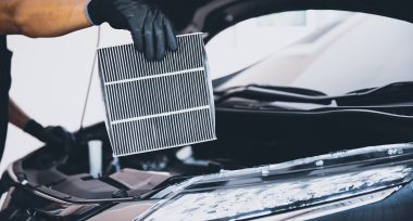 Hand of mechanic holding car air filter old and dirty with dust stains for checking cleaning and replacing new filter. Concept of car care service maintenance.
